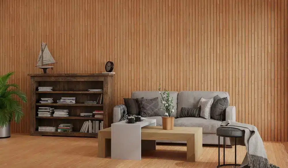 Un salon chaleureux avec un canapé gris agrémenté de coussins, une table basse en bois et une bibliothèque. Des tons chauds et une plante en pot créent une ambiance apaisante.
