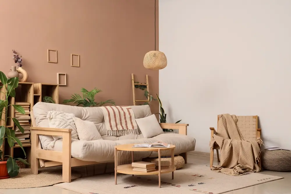 Salon chaleureux avec un canapé beige, de nombreux coussins moelleux et un plaid à rayures. La décoration comprend des plantes, des étagères à livres et une suspension lumineuse.