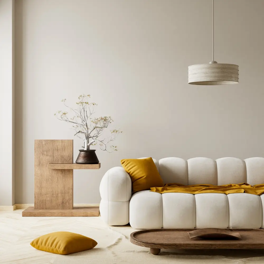 Salon minimaliste avec un canapé blanc capitonné, des coussins moutarde, une table d'appoint en bois, un bonsaï et une suspension lumineuse. Ambiance chaleureuse et sereine.